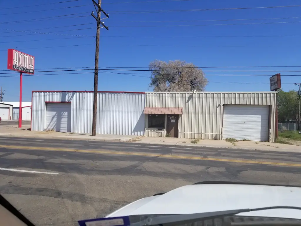 Wide street view of the red ACME BODY SHOP pole sign on Ong Street